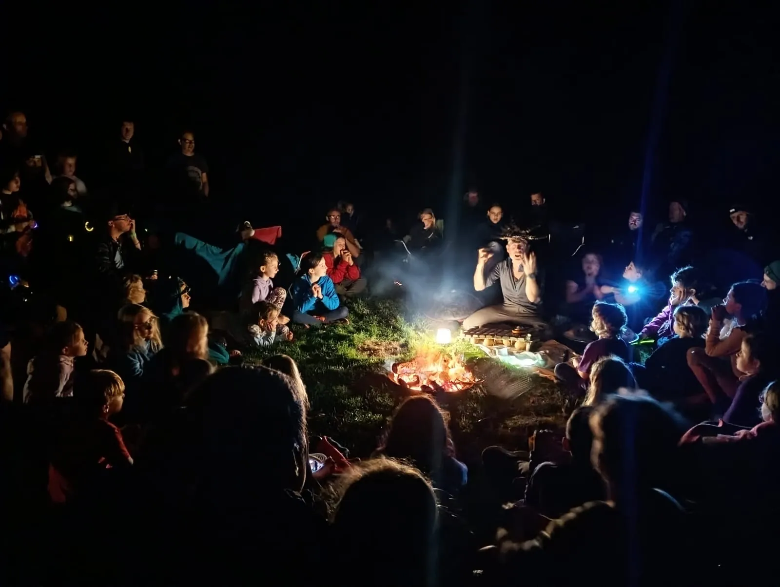 Families gathered around a campfire after dark at DadFest in the UK